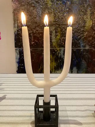 Et tredelt stearinlys med tre flammer i en lysestage på alteret i Tornbjerg kirke 