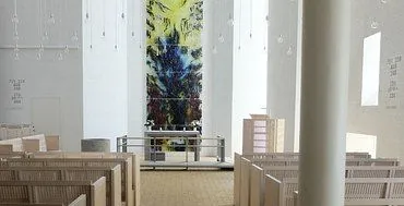 Det fredfyldte interiør i Tornbjerg Kirke med træbænke, et centralt alter og blød naturlig belysning skaber en fredelig atmosfære.