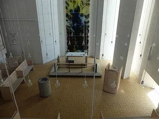 Interiøret i Tornbjerg Kirke, en moderne kirke med højt til loftet, hvide vægge og hængende lyspærer. 